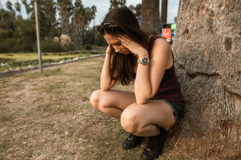 vrouw in zwarte tanktop en korte broek zittend op bruine rots