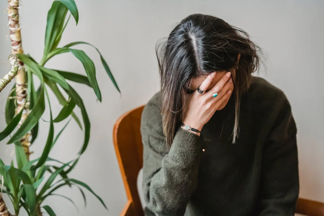 vrouw in grijze trui die gezicht bedekt met haar