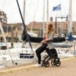 Jonge vrouw die aan een marina zit met een rollator. Stedelijke levensstijl scène.